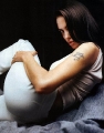 Angelina Jolie laying, showing tatoo